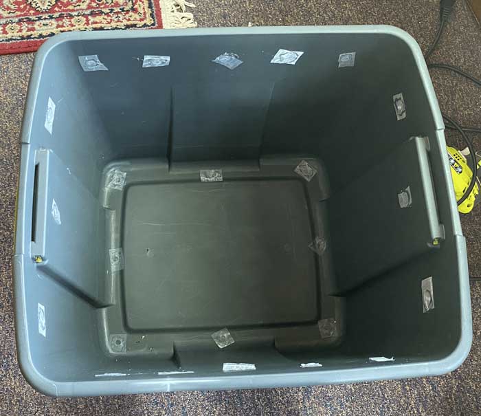 A gray 20 gallon storage tote with the lid off. Holes have been drilled in the bottom and sides,