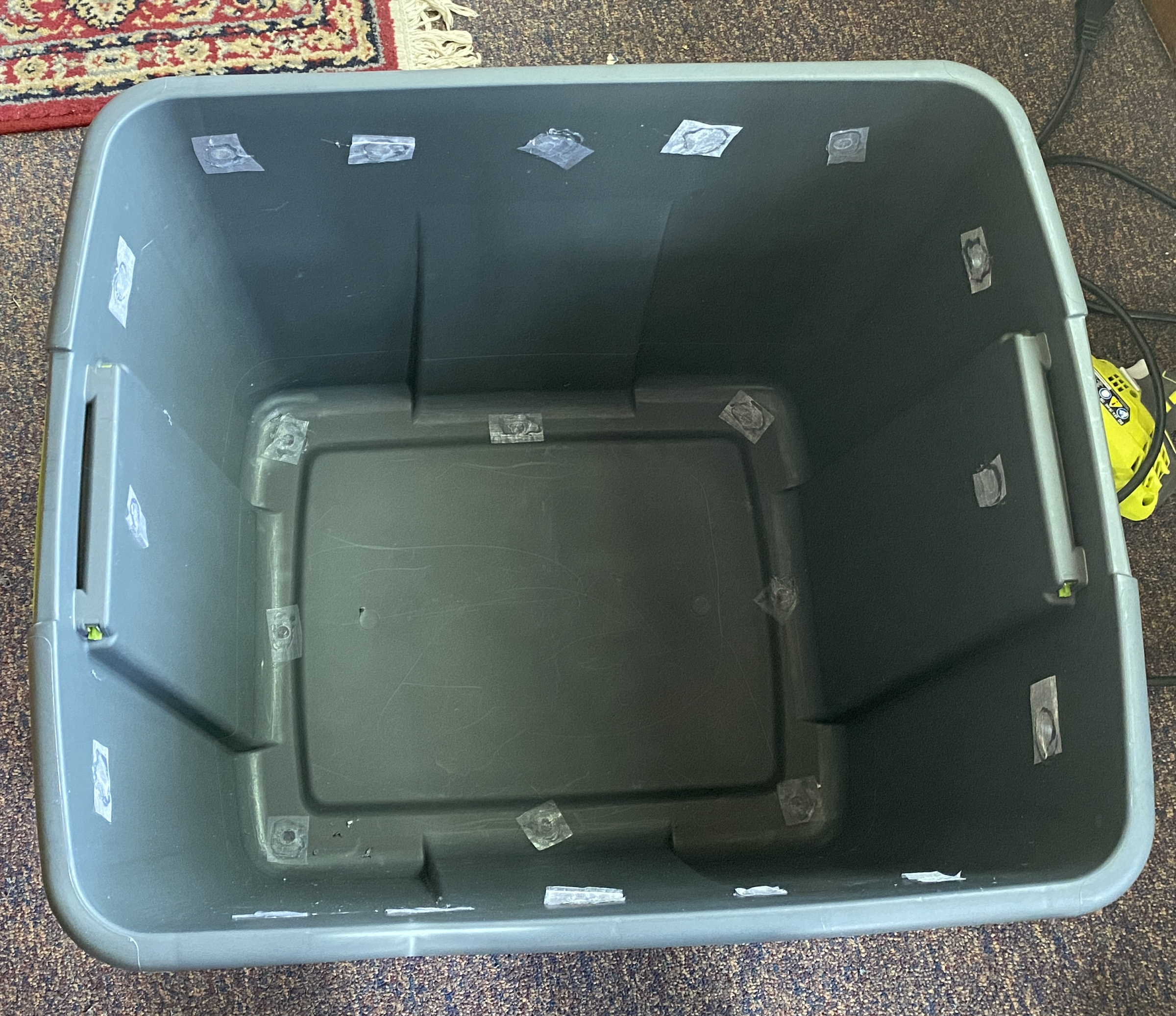 A gray 20 gallon storage tote with the lid off. Holes have been drilled in the bottom and sides,